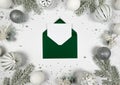 Christmas composition, green envelope, white and silver decorations, fir tree branches, silver stars confetti on white background. Royalty Free Stock Photo
