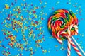 Christmas composition. Large lollipop, red and white striped candies and multicolor round candies on a blue background. Flat lay,