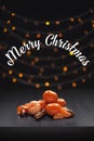 Christmas composition. Mandarins and cinnamon on black background of blurred defocused multicolor lights. Christmas concept