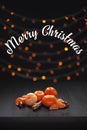 Christmas composition. Mandarins and cinnamon on black background of blurred defocused multicolor lights. Christmas concept