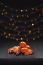 Christmas composition. Mandarins and cinnamon on black background of blurred defocused multicolor lights. Concept