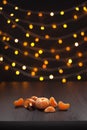 Christmas composition. Mandarins, tangerine slices, tangerine peel on black background of blurred defocused multicolor lights.