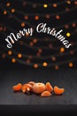 Christmas composition. Mandarins, tangerine slices, tangerine peel on black background of blurred defocused multicolor lights.