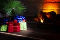 Christmas composition, many colorful gifts under the tree near the burning fireplace, close-up Royalty Free Stock Photo