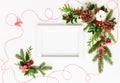 Christmas composition  with photo frame, cotton flower, branches of spruce and holly with red berries on white background. Merry Royalty Free Stock Photo