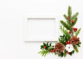 Christmas composition  with photo frame, cotton flower, branches of spruce and holly with red berries on white background. Merry Royalty Free Stock Photo