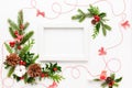 Christmas composition  with photo frame, cotton flower, branches of spruce and holly with red berries on white background. Merry Royalty Free Stock Photo