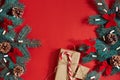 Christmas composition of pine cones, spruce branches and stack of gift boxes on red background Royalty Free Stock Photo