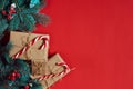 Christmas composition of pine cones, spruce branches and stack of gift boxes on red background