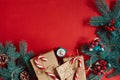 Christmas composition of pine cones, spruce branches and stack of gift boxes on red background Royalty Free Stock Photo