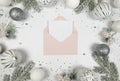 Christmas composition, pink envelope, white and silver decorations, fir tree branches, silver stars confetti on white background. Royalty Free Stock Photo