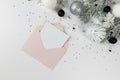 Christmas composition, pink envelope, white and silver decorations, fir tree branches, silver stars confetti on white background. Royalty Free Stock Photo