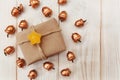 Christmas composition.Present box with twine and craft paper,golden acorns.White wooden table,jujube stars