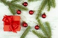 Christmas composition. Red gift, branches of spruce, red ornaments on a light wooden background background. Christmas