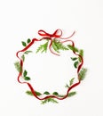 Christmas composition  with red ribbon, branches of spruce and holly  in shape of Christmas bauble on white background. Merry Royalty Free Stock Photo