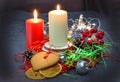 Christmas composition: red and white burning candles on a festive table on a dark background. Gingerbread, tinsel, festoon. Royalty Free Stock Photo