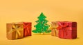 Christmas composition with selective focus. Gift boxes and Christmas tree on a yellow background with copy space