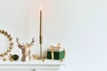 Christmas composition on the shelf in the living room interior. Beautiful decoration. Christmas trees, candles, stars, light and Royalty Free Stock Photo