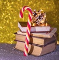 Christmas Composition. Striped Candy Cane, Books And Pine Cone On A Gold Background. Copy Space.