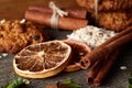 Christmas composition with chocolate biscuits, cinnamon and dried oranges on wooden background, close-up.