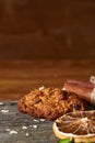 Christmas composition with chocolate biscuits, cinnamon and dried oranges on wooden background, close-up.