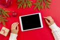 Top view to woman hands with tablet computer and Christmas present box on red background Royalty Free Stock Photo
