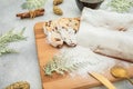 Christmas composition with traditional stollen cake on a wooden board, cutlery and gift on gray