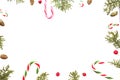 Christmas composition on white background. Xmas frame with candy canes, green thuja twigs, pine cones and red wild rose Royalty Free Stock Photo