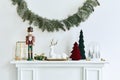 Christmas composition on the white chimney at the living room interior with beautiful decoration. Christmas tree and wreath. Royalty Free Stock Photo