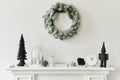 Christmas composition on the white chimney at the living room interior with beautiful decoration. Christmas tree and wreath. Royalty Free Stock Photo