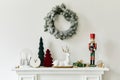 Christmas composition on the white chimney at the living room interior with beautiful decoration. Christmas tree and wreath. Royalty Free Stock Photo