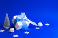 Christmas composition. White gift box with blue ribbon, winter tree, Snowflakes and Silver balls in xmas decorations on blue Royalty Free Stock Photo
