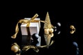 Christmas composition. White gift box with golden ribbon, New Year balls and winter tree in xmas composition on black background Royalty Free Stock Photo