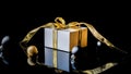 Christmas composition. White gift box with golden ribbon, New Year balls and winter tree in xmas composition on black background Royalty Free Stock Photo