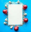 Christmas composition. White mockup blank and red baubles on bright blue background. Royalty Free Stock Photo