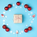 Christmas composition. Wreath made of snowflakes, red balls and lollipops on pastel blue background. Gift in the center. Flat lay Royalty Free Stock Photo