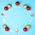 Christmas composition. Wreath made of snowflakes, red, gold balls and lollipops on pastel blue background. Flat lay, top view Royalty Free Stock Photo