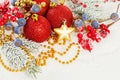 Christmas composition with  Xmas tree branch, red holly berries, golden garland and red baubles on white snow background Royalty Free Stock Photo