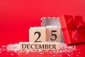 Christmas concept. Close up photo of wooden cube calendar showing date of christmas and an open red giftbox with red ribbon Royalty Free Stock Photo