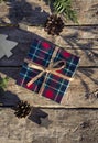 Christmas concept composition with tartan pattern gift box on the old weathered wooden table. Winter holiday greeting card