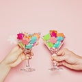 Christmas concept with couple hands holding wine glasses with colorful Xmas decoration on pastel pink background Royalty Free Stock Photo