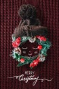 Christmas concept Cute baby made from a wreath, knitted hat and illustration on a red knitted background. Minimal winter Royalty Free Stock Photo