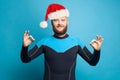 Christmas concept. Happy man diver in Santa cap holding okay sign standing on blue background Royalty Free Stock Photo