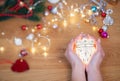 Christmas concept. Human hands hold a ceramic christmas decoration in a shape of glowing heart Royalty Free Stock Photo