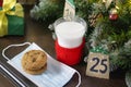 Christmas concept with milk and cookies for Santa. Advent calendar, caronavirus medical mask and Christmas traditions Royalty Free Stock Photo