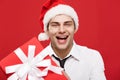 Christmas Concept - portrait close-up Santa christmas businessman over red background giving red gift to camera. Royalty Free Stock Photo