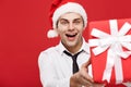 Christmas Concept - portrait close-up Santa christmas businessman over red background giving red gift to camera. Royalty Free Stock Photo