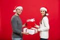 Christmas Concept - Young attractive couple giving gifts to each other celebrating in Christmas day Royalty Free Stock Photo