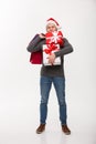 Christmas Concept - young handsome man with beard holding heavy presents and shopping bags with exhausted facial Royalty Free Stock Photo