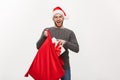 Christmas Concept - Young happy beard man excite with big present in santa bag.